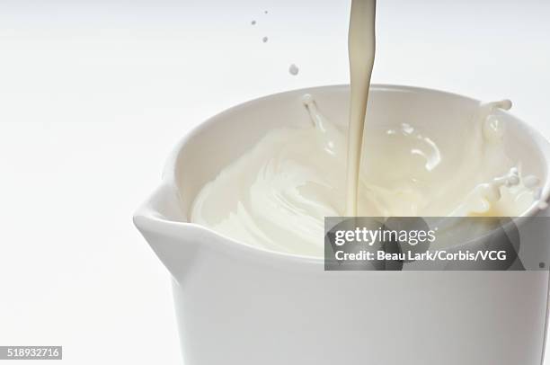 creamy milk poured into pitcher - milk pitcher ストックフォトと画像