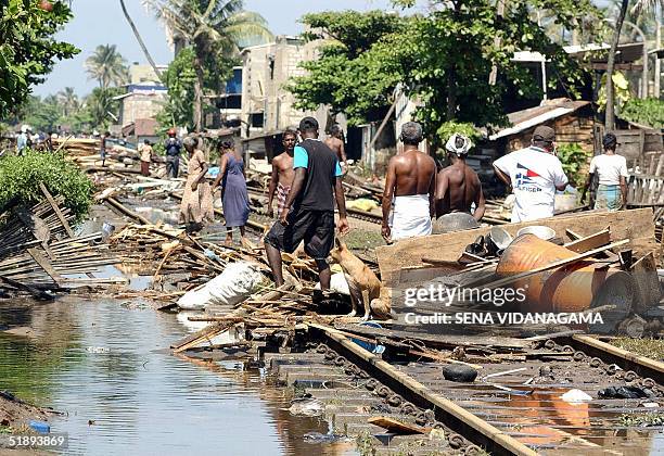 Residents swift through the trail of destruction along the coastal railway line in the southern Sri Lankan town of Lunawa 26 December 2004 after...