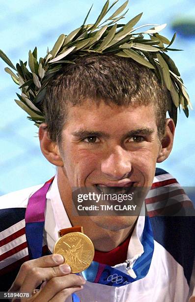 Foto tomada el 17 de agosto de 2004 del estadounidense Michael Phelps celebrando en el podio tras ganar la medalla de oro en los 200m en los Juegos...