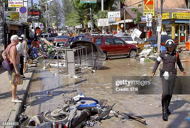 Foreign tourists look at damage caused by a tsunami in Phuket island, southern of Thailand, 26 December 2004. At least 118 people were killed and...