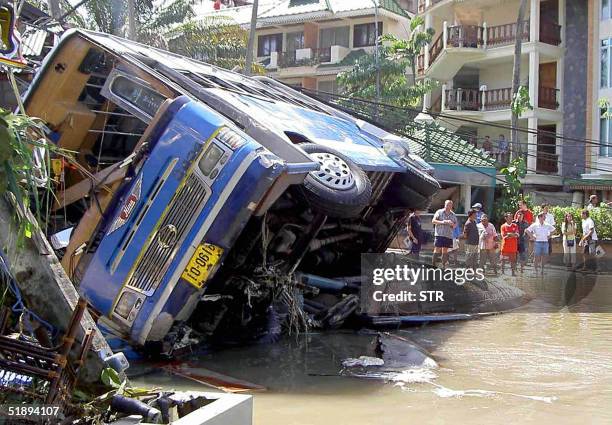 Foreign tourists look at damage caused by a tsunami in Phuket island, southern of Thailand, 26 December 2004. At least 118 people were killed and...