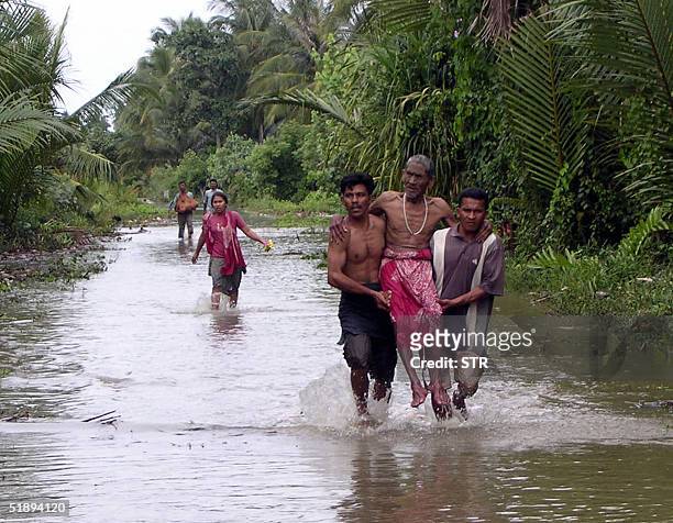 Residents of Kuala Keureutoe village, Ranah Pasir flee from their homes which surrounded by water after the strong quake early Sunday, 26 December...