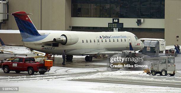 Airline workers clean up snow and ice near a Comair plane at Cincinnati Northern Kentucky International Airport December 26, 2004 in Hebron,...