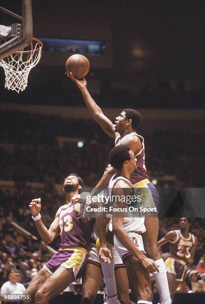 Magic Johnson of the Los Angeles Lakers jumps to shoot against the New York Knicks as teammate Kareem Abdul Jabbar watches at Madison Square Garden...