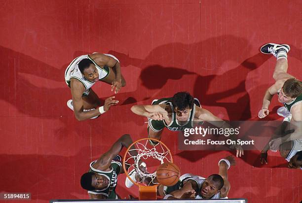 Boston Celtics Kevin McHale watches his shot as his teammates and Milwaukee Bucks players jump to catch the rebound at the basket during a game circa...