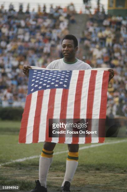 June 15th 1975, New York Cosmos' Pele holds an American flag on the field.