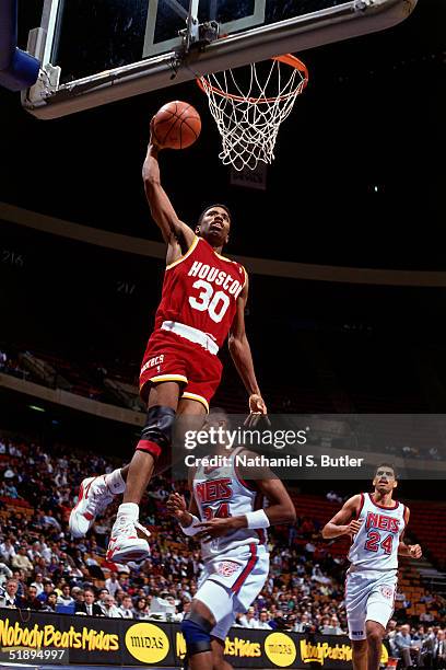Kenny Smith of the Houston Rockets drives to the basket for a slam dunk against the New Jersey Nets during an NBA game at the Brendan Byrne Arena in...