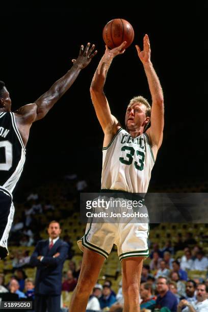 Larry Bird of the Boston Celtics shoots a jumpshot against David Robinson of the San Antonio Spurs during an NBA game in 1991 at the Boston Garden in...