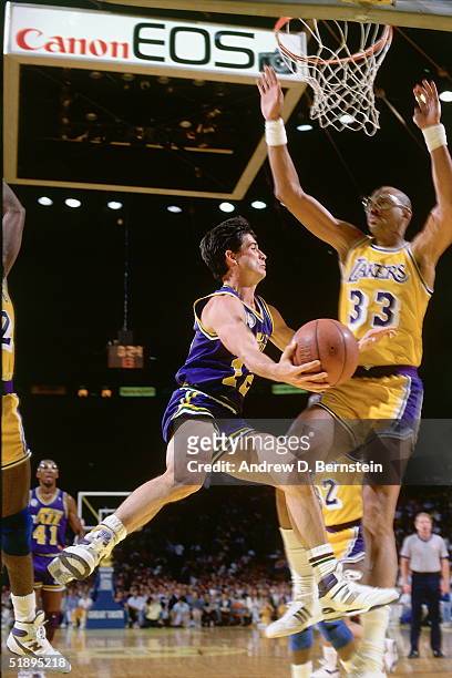 John Stockton of the Utah Jazz looks to make a pass around Kareem Abdul-Jabbar of the Los Angeles Lakers during the NBA game at the Forum in Los...