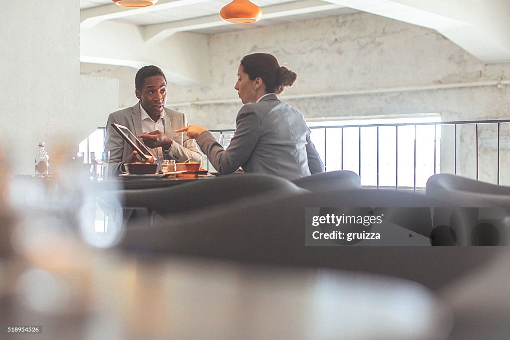 Jovem mulher de negócios e Homem de negócios, tendo uma conversa no restaurante