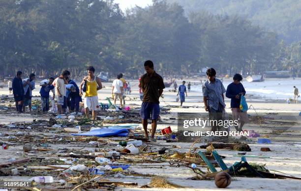 People walk through debris along the shoreline of Pathong beach of Phuket island, southern Thailand, 27 December 2004, a day after a tidal wave...