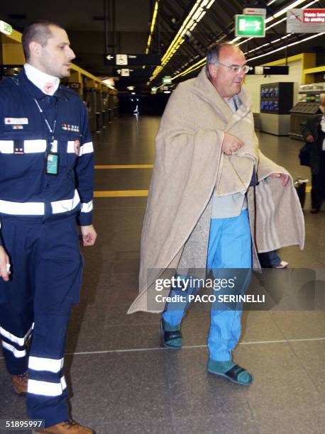 An Italian tourist wearing a blanket provided by the Italian Red Cross, as he hastily left from Male, Maldives Island in summer outfits, is flanked...