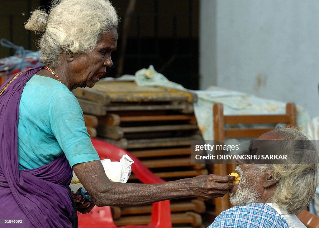 An elderly Indian lady feeds her disable