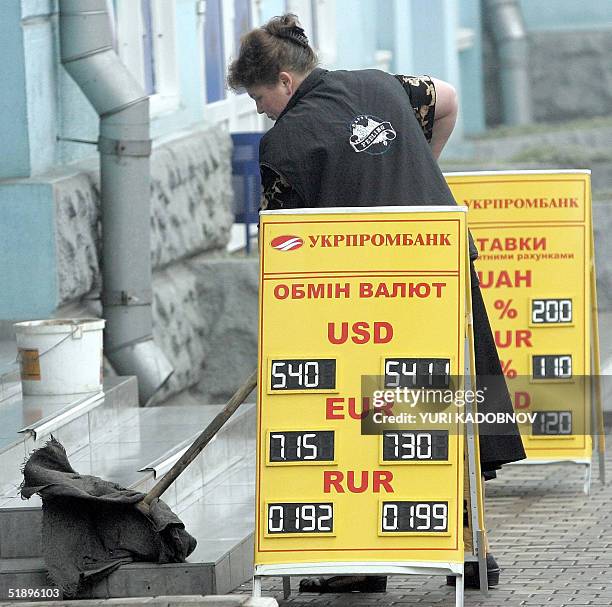 Ukrainian woman cleans front steps of a currency exchange point in central Donetsk, eastern Ukraine, stronghold of Prime minister Viktor Yanukovich,...
