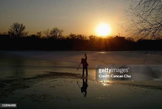 Chinese man clears some ice from Shishahai Lake for swimming December 27, 2004 in Beijing, China. The lake is a popular spot for people who love...