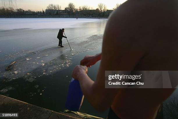 Chinese man clears some ice from Shishahai Lake for swimming December 27, 2004 in Beijing, China. The lake is a popular spot for people who love...