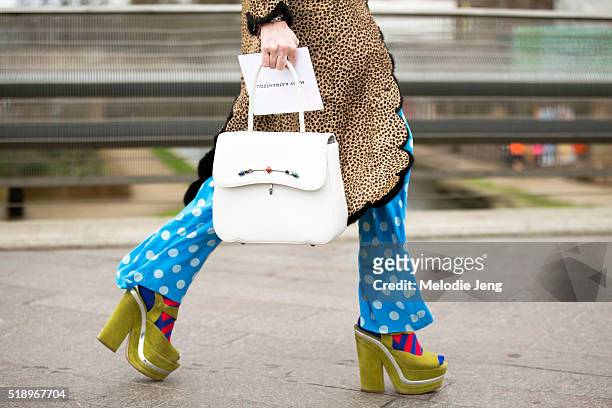 Showgoer wears a quirky leopard-print jacket with black lining, light-blue polka dot trousers, a white purse, red and blue striped socks, and green...
