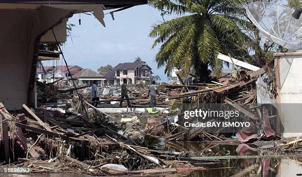 Residents of Banda Aceh walk through a scene of destruction, 27 December 2004 following a devastating quake and series of tidal waves that struck the...