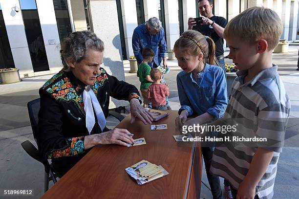 Dr. Temple Grandin, left, autographs her inventor's trading card for Liam McAlpine right and Julia Todd middle, outside of the US Patent and...