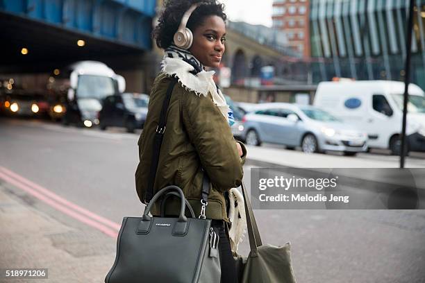 Model Tara Falla exits the Osman show in silver Beats headphones, a green jacket, and a Karl Lagerfeld purse during London Fashion Week Autumn/Winter...