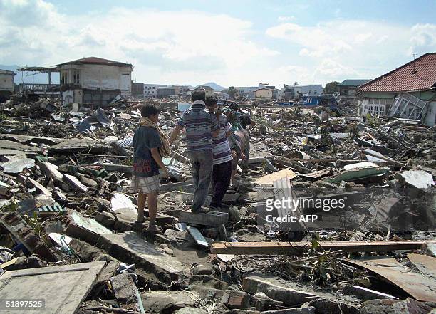 This photo taken 27 December 2004 shows local residents in Banda Aceh carrying away the body of a dead relative the day after a devastating 9.0...
