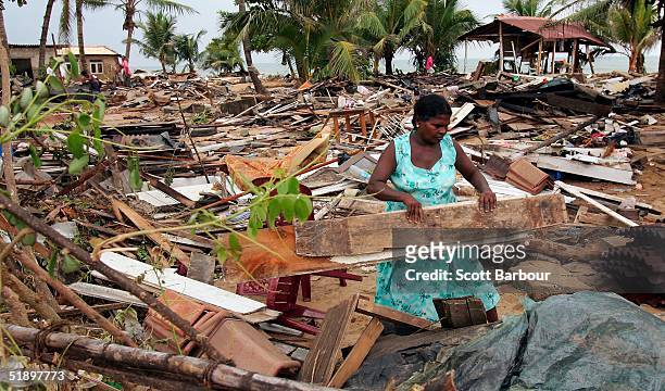 Woman clears away debris from where her home once stood after the massive tsunami wave swept across coastal Sri Lanka, December 28, 2004 in Colombo,...