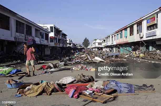 Man walks amid dead bodies and debris thrown around by a Tsunami that hit the Indonesian City of Banda Aceh - 150 miles from southern Asia's massive...