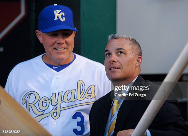 Ned Yost manager of the Kansas City Royals talks with general manager Dayton Moore prior to a game against the New York Mets on opening day at...