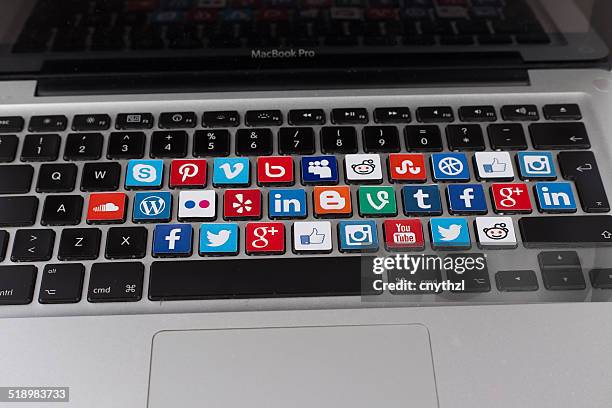 social media logos on macbook keyboard - macbook business stockfoto's en -beelden
