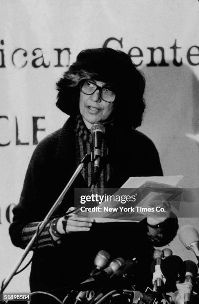 American author and critic Susan Sontag reads from a document as she stands behind a podium behind a bank of microphones at the 'Writers in Support...