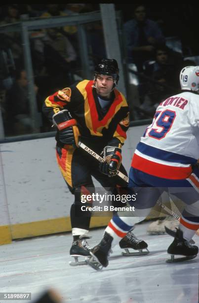 Canadian hockey player Dennis Kearns of the Vancouver Canucks keeps a close eye on the action as Bryan Trottier of the New York Islanders during a...