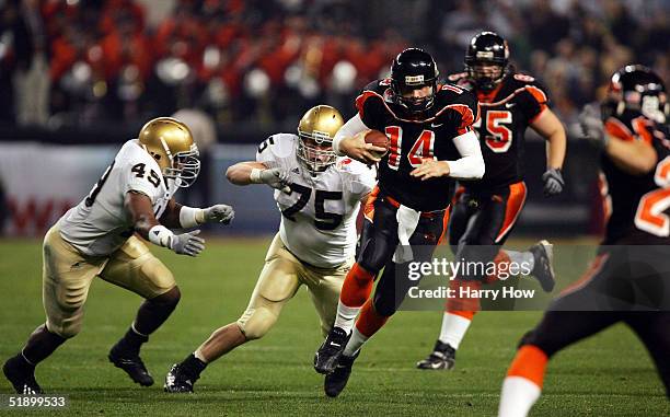 Derek Anderson of Oregon State scrambles away from Chris Frome and Rich Whitmey III of Notre Dame in the first quarter during the Insight Bowl at...