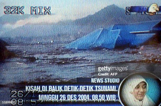 This still grab taken 29 December 2004 from video shot 26 December 2004 shows a wave sweeping away houses in Banda Aceh, with the video shooter Putri...