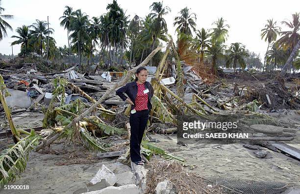 Thai women stands among the debris of a washed away house in Khao Lak, north of the devastated Thai tourist resort island of Phuket, 29 December...