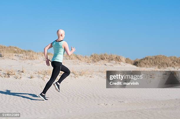 young woman with bald head jogging after chemotherapy - lymphoma stock pictures, royalty-free photos & images