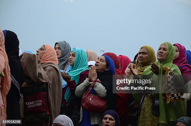 Kashmiri Muslim women raise their hand in prayers as the head priest displays the relic, believed to be the hair from the beard of the Prophet...