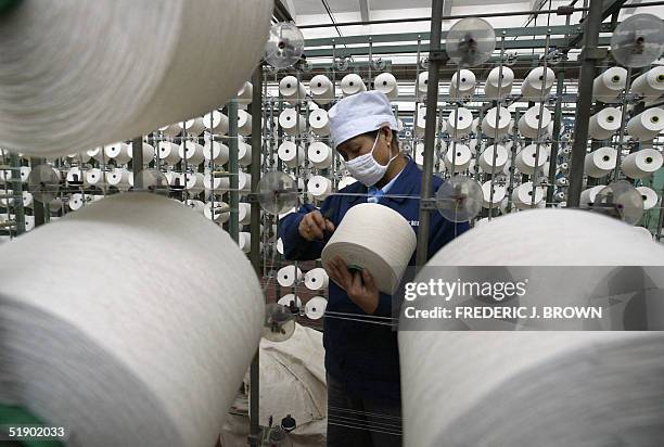 Worker at the state-owned Shijiazhuang Changshan Textile factory prepares to unfurl a roll of cotton thread in the mechanized process of producing...