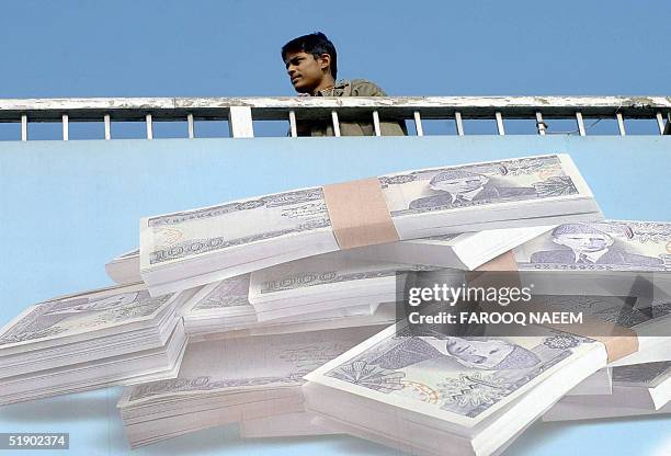 Pakistani youth walks over a bridge upon which a billboard shows Pakistani currency in Rawalpindi, 30 December 2004. Pakistan's economy is expected...