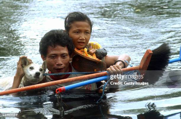 Man, girl and dog cross deep water at Sirombu village December 29, 2004 in Nias, North Sumatra, Indonesia. Tens of thousands of people have been...