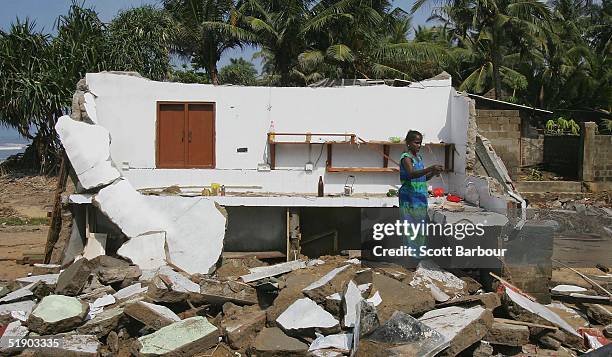 Woman cooks amongst the wreckage of her home after a massive tsunami wave swept across coastal Sri Lanka on December 30, 2004 in Kalutura, Sri Lanka....