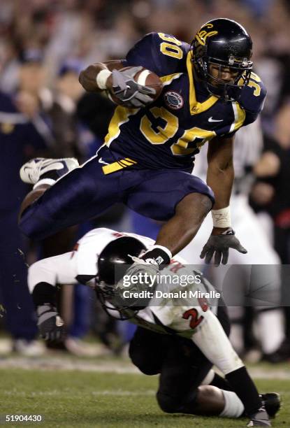 Tailback J.J. Arrington of the California Golden Bears hurdles over the tackle of cornerback Khalid Naziruddin of the Texas Tech Red Raiders during...