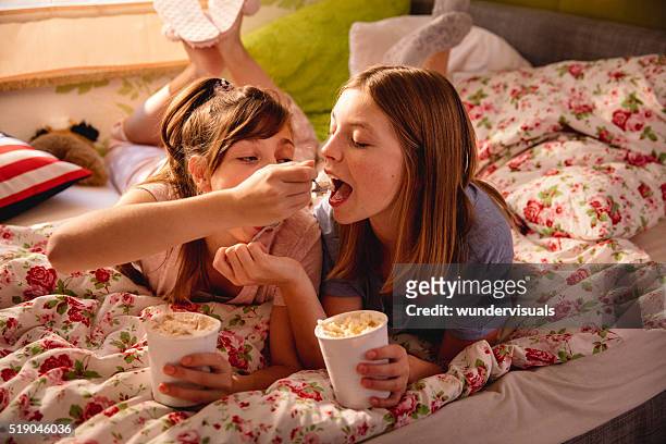 girl feeding her friend ice cream from a tub - lying down friends girls stock pictures, royalty-free photos & images