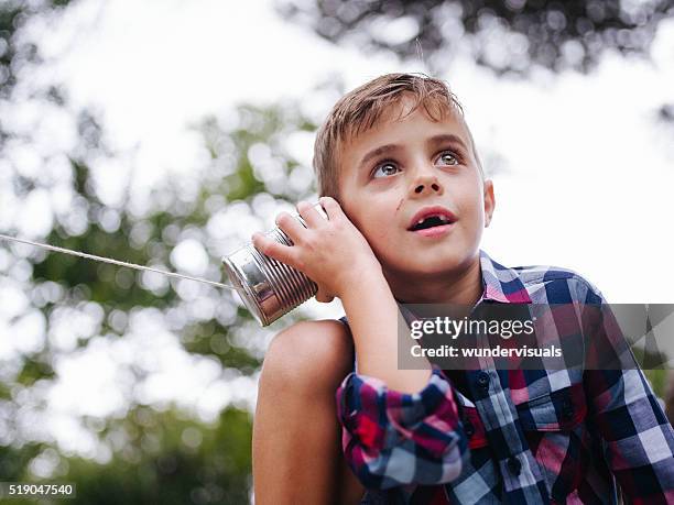 niedrige winkelansicht der jungen zuhören auf dosentelefon - tothless boys stock-fotos und bilder