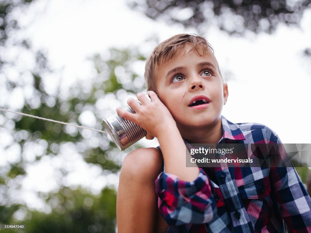 Low angle view of Boy listening on tin can phone