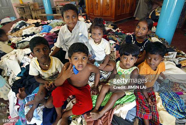 Sri Lankan young children sit on top of a huge pile of donated clothes at a refugee camp set up in a Buddhist temple in the southwestern coastal town...