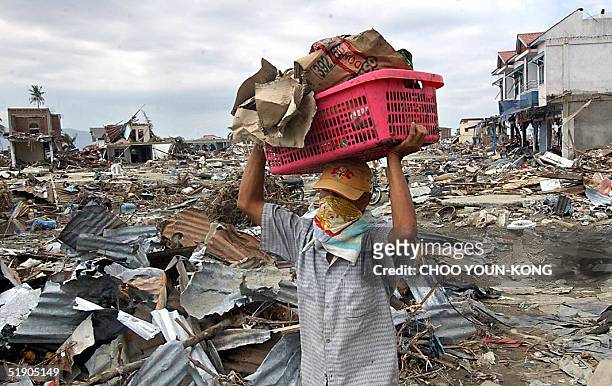 An Indonesian man carries some belongings from his damaged shop in Banda Aceh, 31 December 2004, six days after the powerful earthquake and resulting...