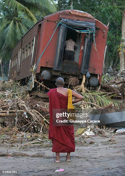 Monk stands near a wrecked train car December 30, 2004 near Galle, Sri Lanka. The death toll from the tsunami in Indian Ocean has reached 130,000...