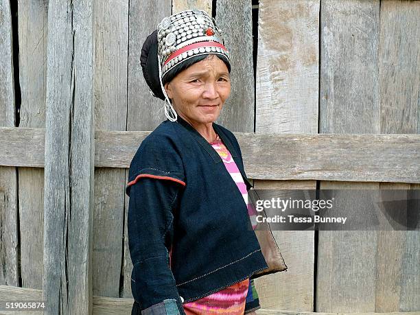 An Akha ethnic minority woman wearing traditional clothing made from home grown, indigo dyed cotton outside her home, Ban Lakham, Luang Namtha...