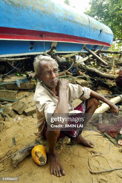 Sri Lankan fisherman sits by his upturned boat amidst wreckage caused by the recent Tsunami in the southwestern coastal town of Dondanduwa, 01...