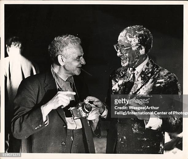 Polish-born American photographer Weegee shows his camera to British actor and comedian Peter Sellers , covered in pie filling and in costume as...